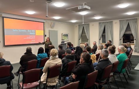 a community meeting with people sitting and watching someone address the room
