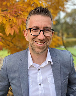Phillip Souter standing in front of a tree with autumn leaves