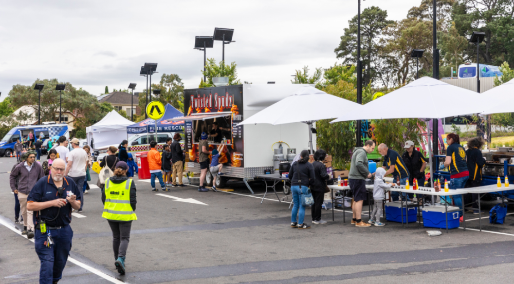 photo of festival, there are food trucks and people walking 