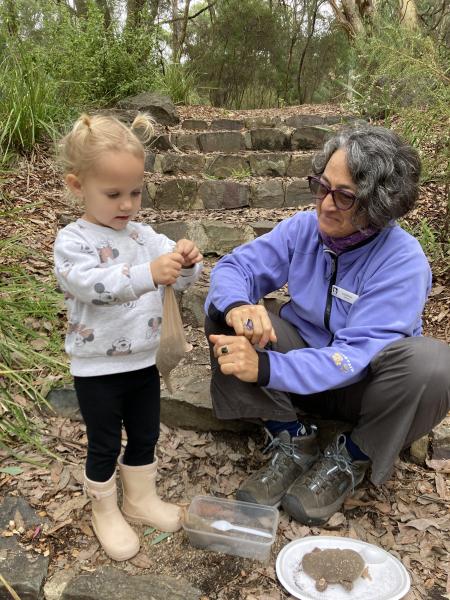 Preschool age girl with volunteer making a craft in the bush.