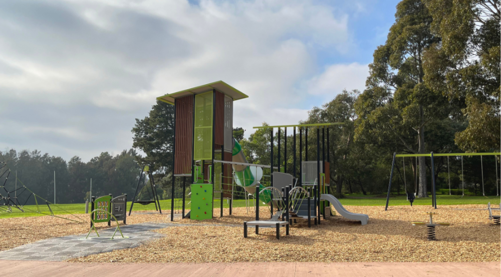 playspace with green climbing wall and marron poles