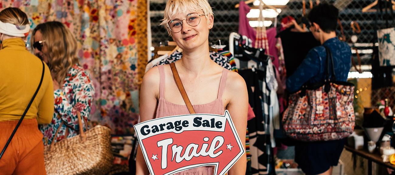 lady in a pink dress holding a Garage Sale Trail sign