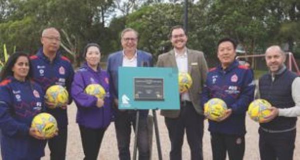 Group of people holding netballs in front of Whitehorse lecturn. 
