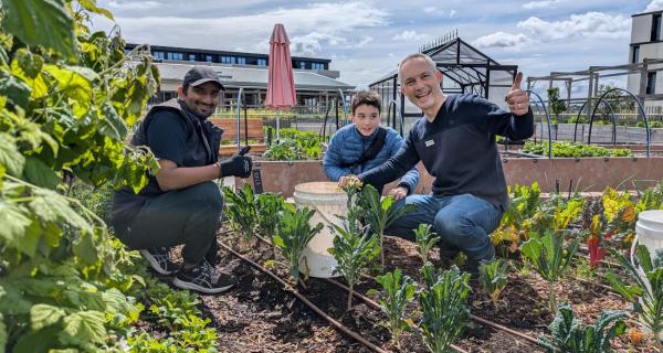 2 men and a child helping at a community gardens