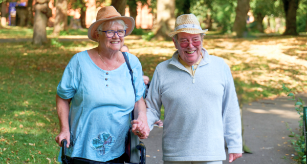 Lady and man walking with frame holding hands 