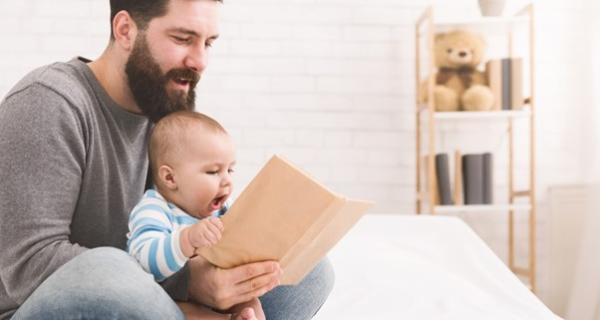 Father reading to young baby that is sitting on his lap