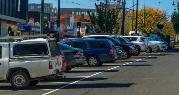 Cars parked along the street in front of a group of shops. 