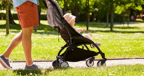 parent walking their child in a pram on a sunny day