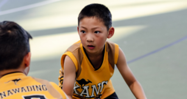 A boy tries to pass the basketball around his mate. 