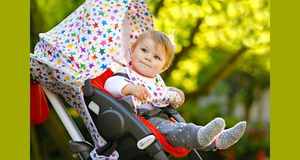 Baby smiling in their brightly coloured pram decorated with stars