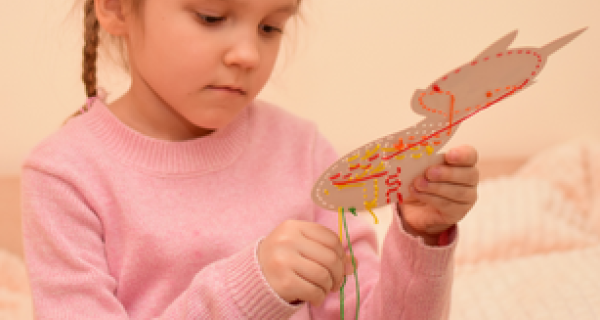 young child threading yarn through a cardboard animal