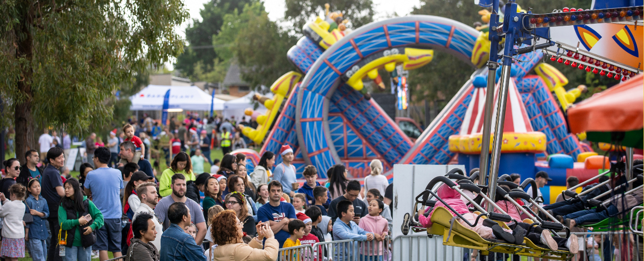 Large crowd of people lining up for colourful amusement rides