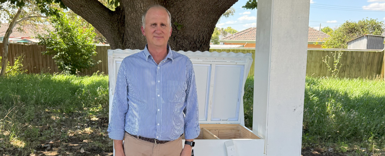 Michael stands next to his beehive