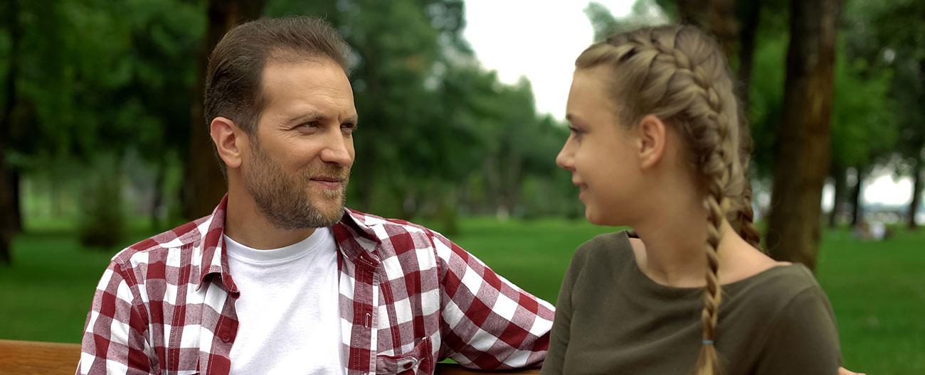 Father talking to daughter on a park bench
